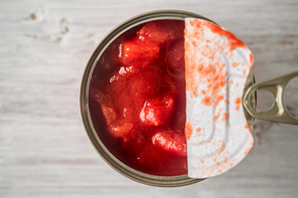 Chopped tomatoes in metal can in wooden table top view
